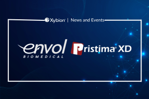 Banner for Xybion News and Events with the Envol Biomedical and Pristima XD logos on a blue backdrop, decorated with light particle effects.