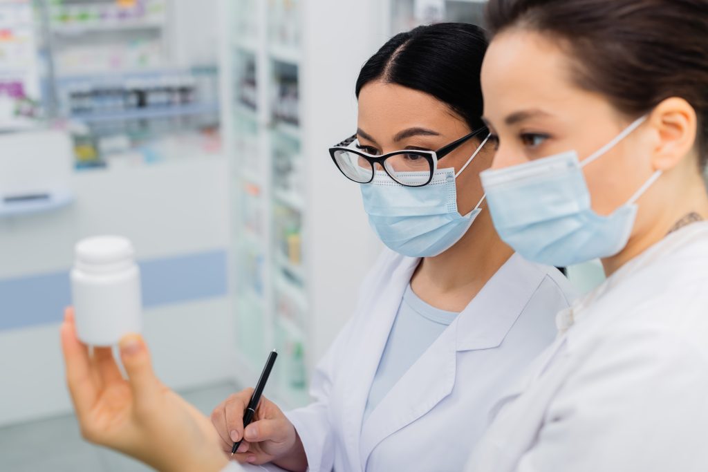 Two scientists in white lab coats analyze a bottle, showcasing teamwork and focus in a laboratory context.