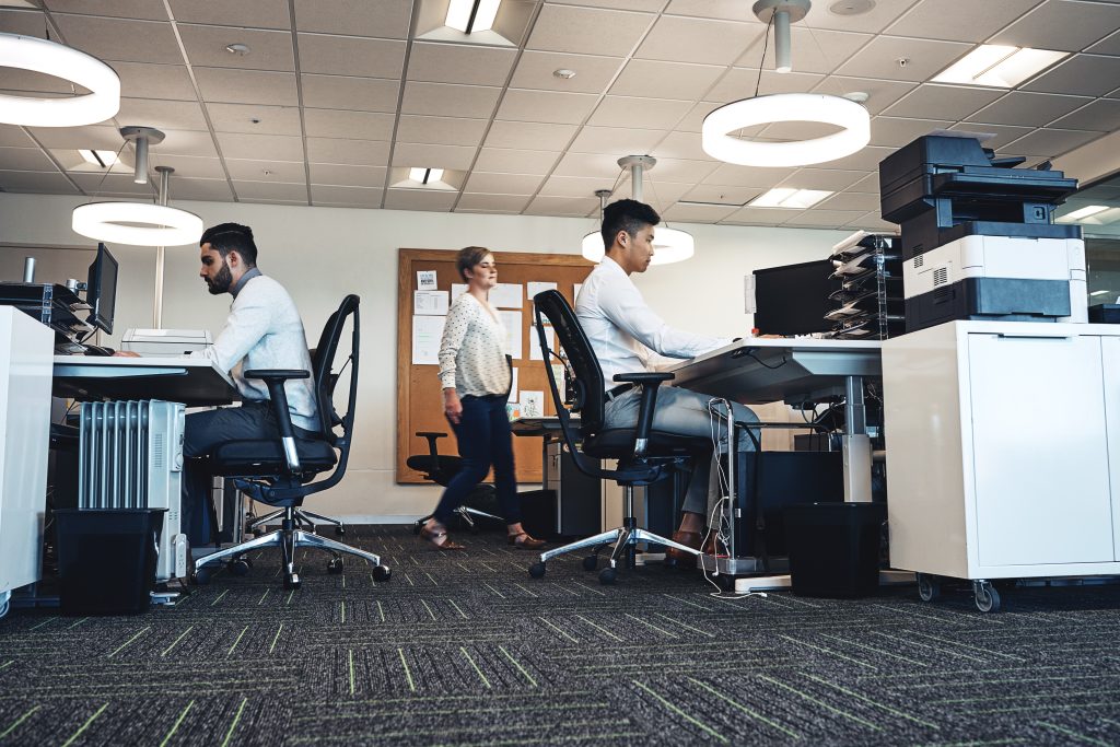Two individuals focused on their tasks at separate desks in a modern office environment.