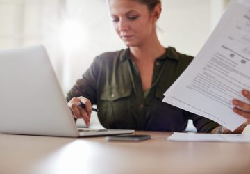 young-woman-with-documents-working-on-laptop-2021-08-26-19-58-30-utc-scaled.jpg